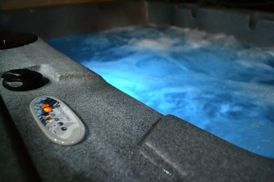 Hot tub lit from within at night, water moving and steam rising