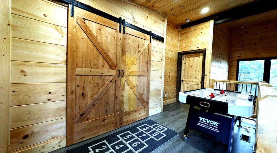 Double sliding barn doors on the landing, air hockey table and a hopscotch rug alongside