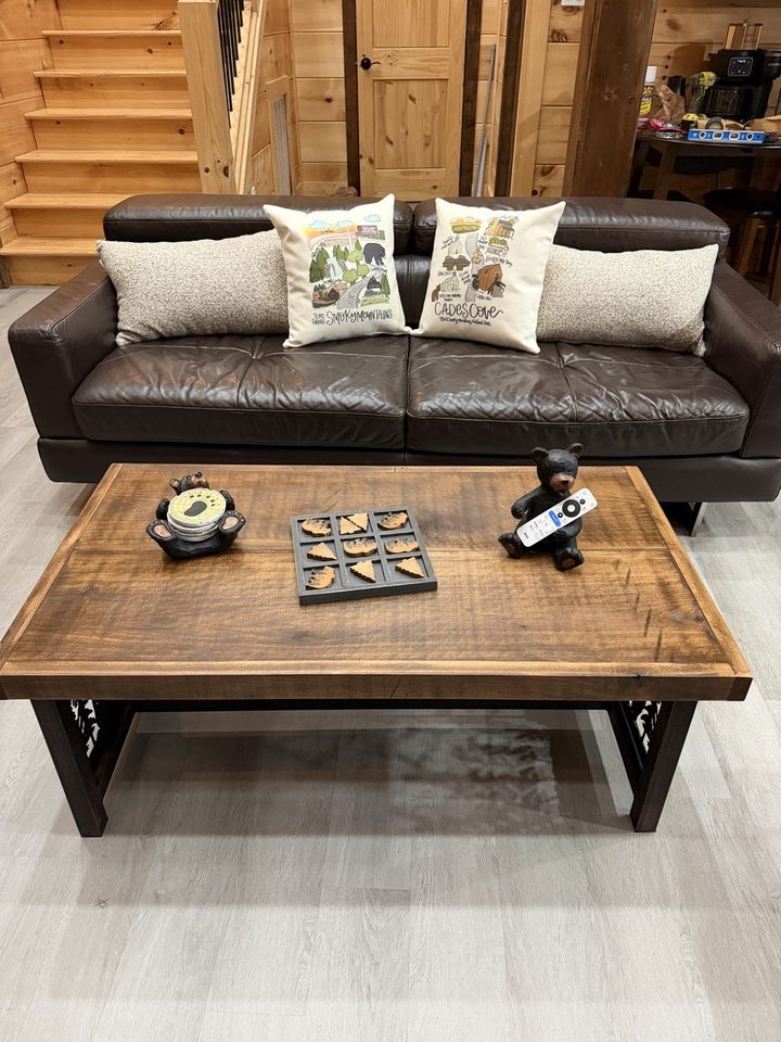 Brown leather sofa with Smoky Mountains and Cades Cove cushions, and a timber coffee table set with carved black bears and a wooden noughts-and-crosses board